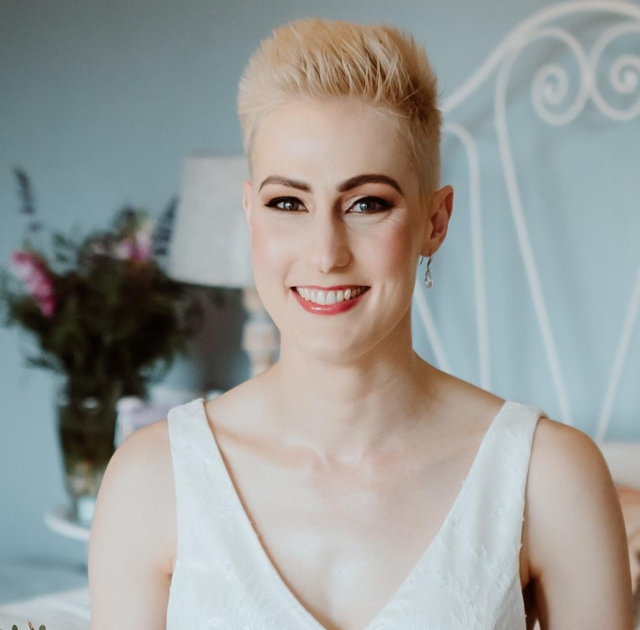 A photo of a woman wearing a white dress in a light blue room.